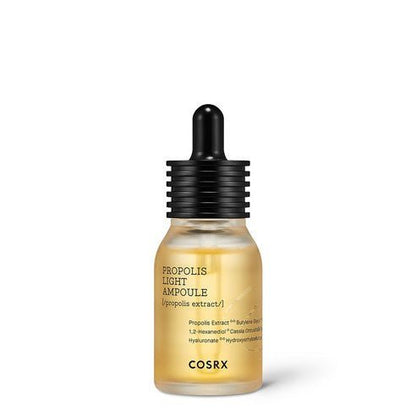 Small frosted glass dropper bottle with golden propolis ampoule and black ribbed cap on white background