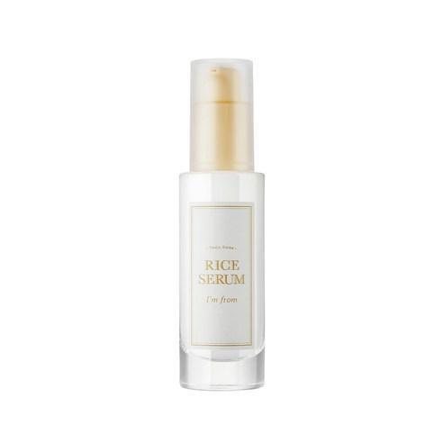 Tall clear frosted glass bottle with white label and gold pump containing brightening rice serum product