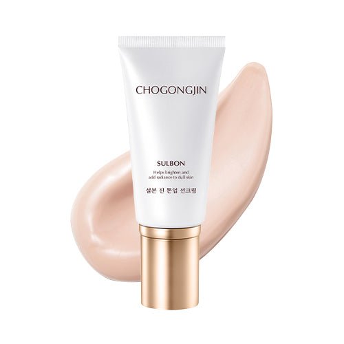 White tube of brightening tone-up sun cream with gold cap and creamy beige swatch behind on white background