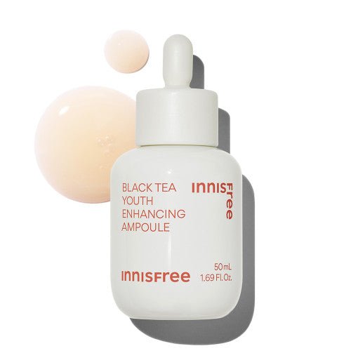 White dropper bottle of Black Tea Youth Enhancing Ampoule with beige liquid droplets on a white background