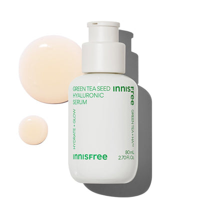 White pump bottle of hydrating green tea seed serum with creamy beige serum drops on white background