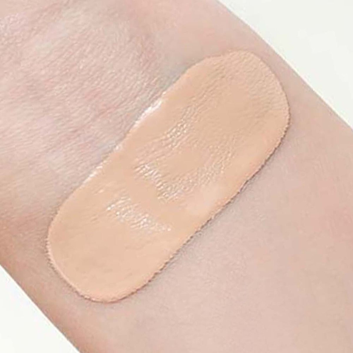 Smooth swatch of light beige cushion powder demonstrating long-lasting coverage on pale skin tone background