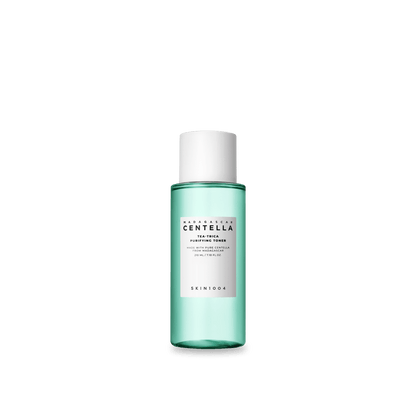 Blue-green translucent bottle of purifying toner with white label and white cap on plain background