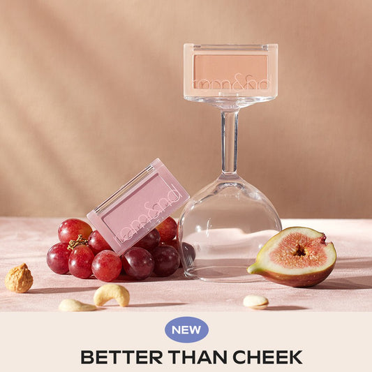 Two rom&nd BETTER THAN CHEEK blush compacts displayed with grapes, fig, and nuts on soft pink surface