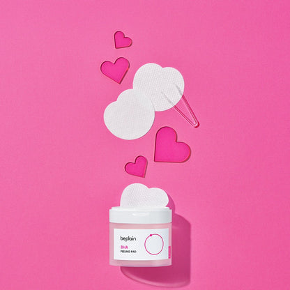 beplain BHA Peeling Pad 50P jar with round textured pads and pink acrylic heart shapes on vibrant pink background for gentle exfoliation
