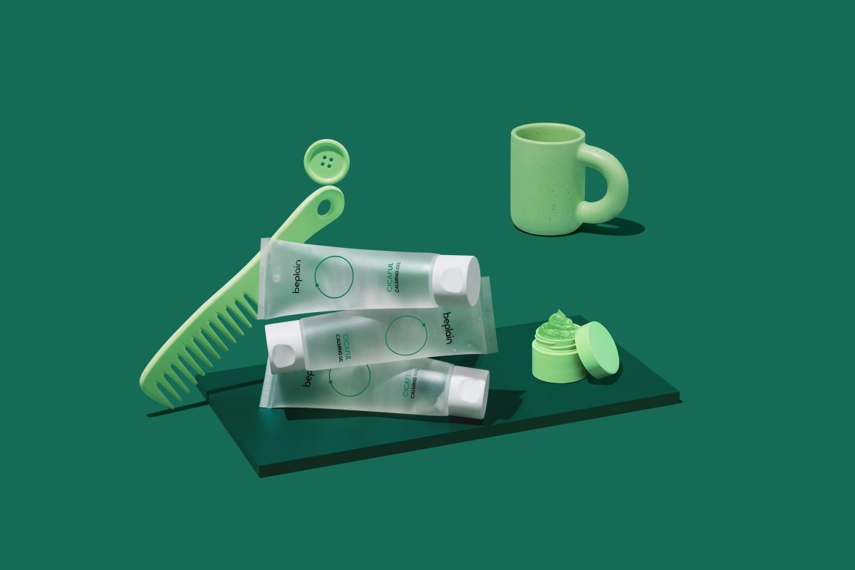 beplain Cicaful Calming Gel 80ml tubes stacked with open jar cream, comb, and cup on dark green surface