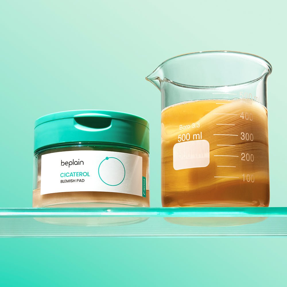 beplain Cicaterol Blemish Pads 70 sheets container with teal lid next to a glass beaker of amber liquid showing cooling effect