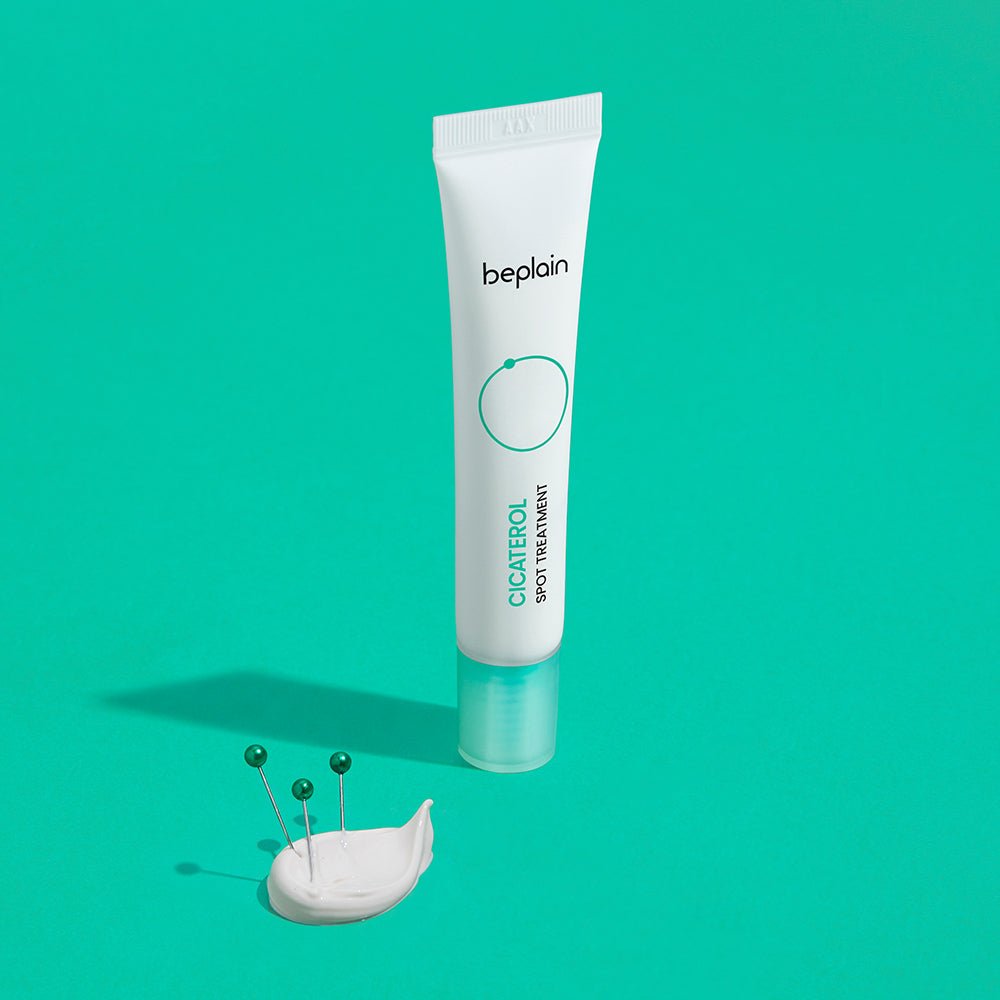 beplain Cicaterol Spot Treatment 15ml in white tube with green cap placed on bright teal background with cream and pins nearby