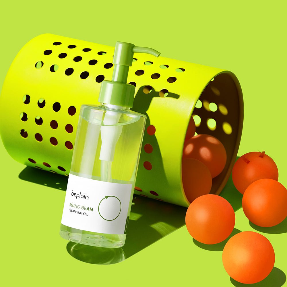 beplain Mung Bean Cleansing Oil 200ml bottle beside lime green basket with orange ping pong balls on lime background