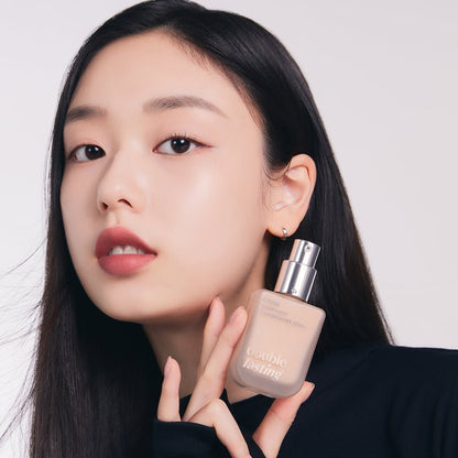 Model with flawless skin holding ETUDE Double Lasting Vegan Cover Foundation SPF32/PA++ 30g bottle with pump dispenser close-up
