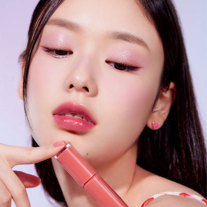 Close-up of a woman with dewy makeup holding ETUDE Fruity Dewy Tint 4.5g, showcasing a hydration boost lip tint effect.