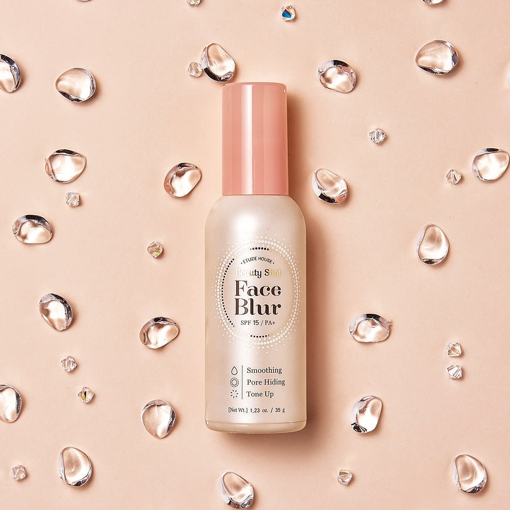 ETUDE Face Blur SPF 33 PA++ 35g in frosted bottle with pink cap surrounded by clear water droplets on beige background