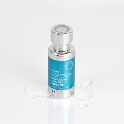 VT Hyaluronic Low 100 Essence 30ml bottle with silver cap surrounded by clear hydration droplets for moisture delivery