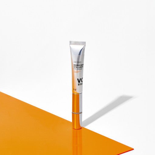 VT Reedle Shot Vita-Light Eye Cream 15ml standing on orange surface, emphasizing wrinkle reduction benefits for eye care.