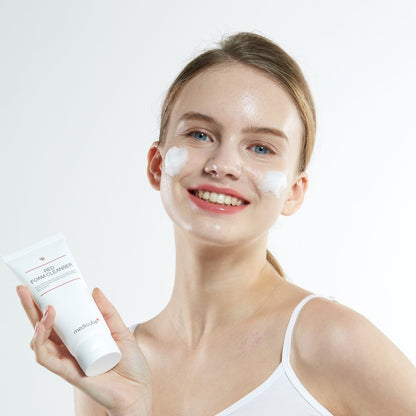 medicube Red Foam Cleanser 120ml held by smiling woman with foam cleanser applied on cheeks for effective cleansing