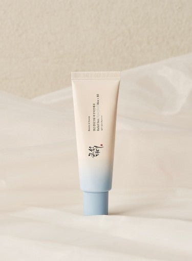 Minimalist tube with soft blue cap containing hydrating sun protection cream on neutral fabric background