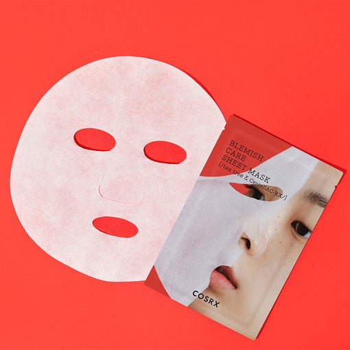 White facial sheet mask next to red and white blemish care mask packaging featuring a close-up face image