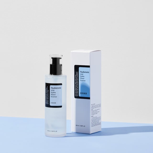 Frosted bottle and light blue box of hydrating essence with pump dispenser on soft blue surface background