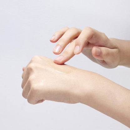 Person gently applying clear serum on the back of their hand showcasing smooth, hydrated skin texture