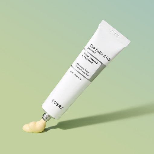 White tube of retinol cream dispensing smooth beige cream on soft green background highlighting wrinkle reduction benefits