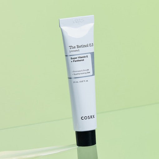 White tube of retinol cream with black cap highlighting vitamin E and panthenol benefits on light green background