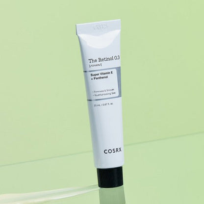 White tube of retinol cream with black cap highlighting vitamin E and panthenol benefits on light green background