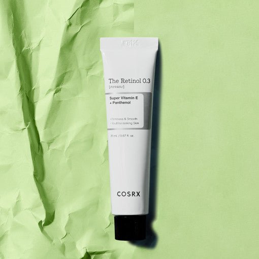 White tube of retinol cream with black cap on textured light green background highlighting wrinkle reduction benefits