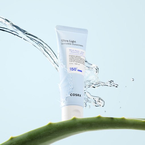 White tube of ultra-light invisible sunscreen with water splash and aloe vera leaf on pale blue background