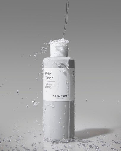 White bottle of hydrating PHA toner with water splashing and droplets on soft gray background