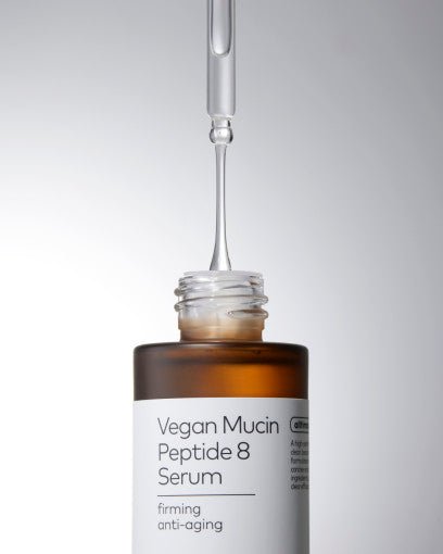 Dropper releasing clear serum above amber glass bottle labeled Vegan Mucin Peptide 8 Serum for firming and anti-wrinkle benefits