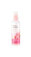 Clear pink spray bottle of cherry blossom hair mist designed for frizz control on white background