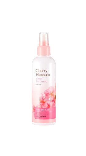 Clear pink spray bottle of cherry blossom hair mist designed for frizz control on white background