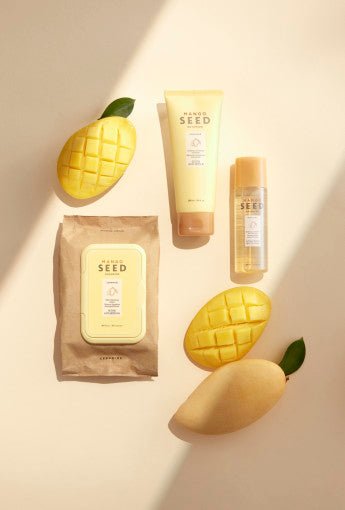 Soft cleansing wipes and skincare tubes arranged with whole and sliced mango fruits on beige background