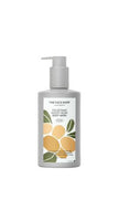 Gray pump bottle of woody musk body wash with orange fruit and green leaf design on white label