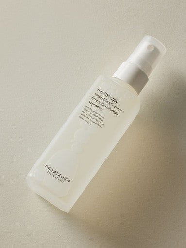 Frosted spray bottle of moisturizing vegan blending mist with minimalist label on a neutral surface