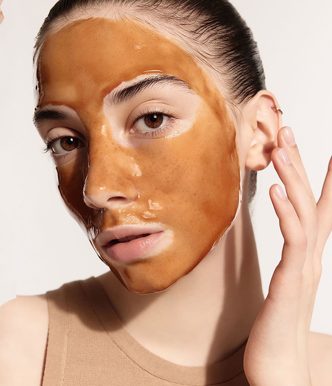 Close-up of woman with smooth, clarifying brown facial mask gently applied emphasizing clear, radiant skin effect
