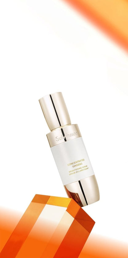 Elegant white and gold serum bottle balanced on a translucent amber geometric block against a bright white backdrop