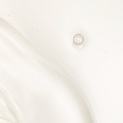Droplet of clear rejuvenating water with tiny bubbles suspended in smooth, translucent liquid texture on white surface