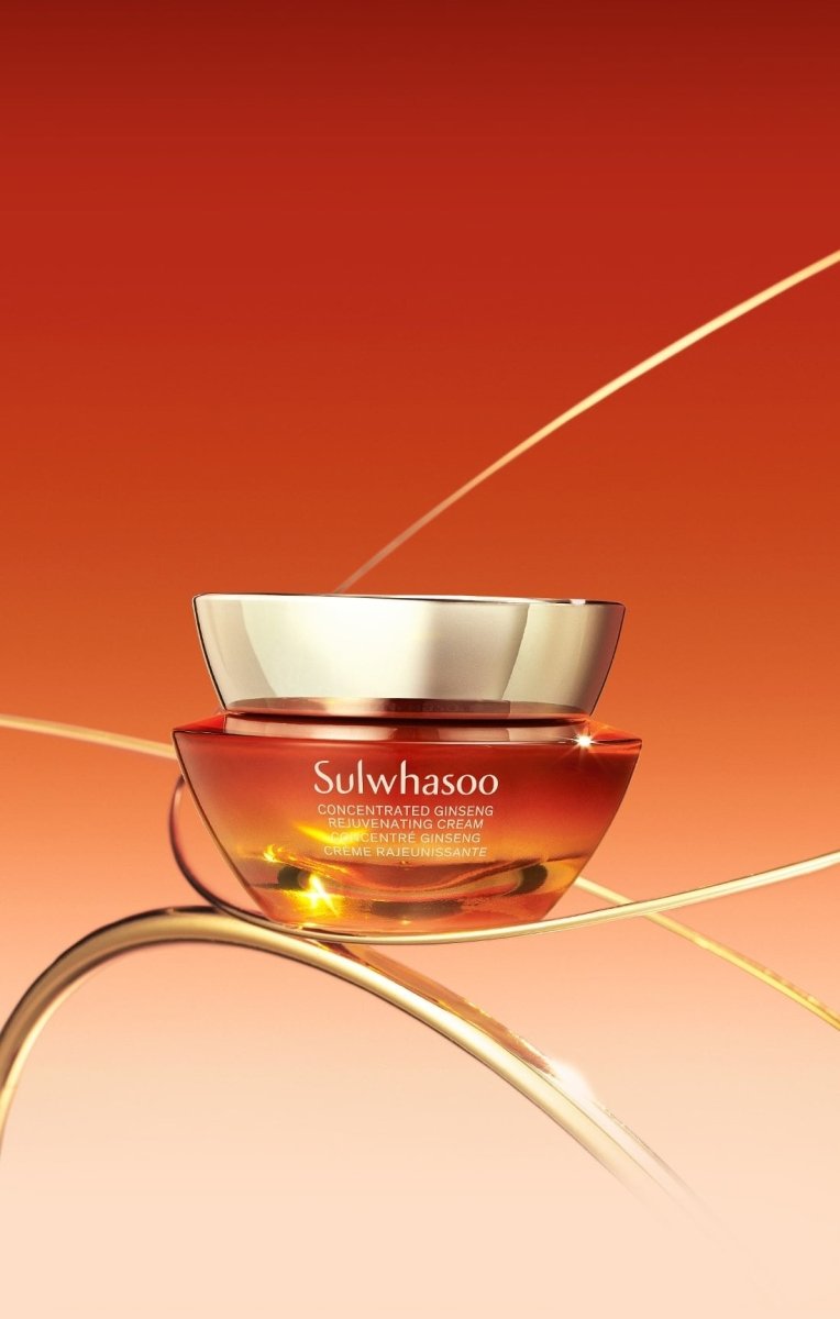 Luxurious amber jar of concentrated ginseng renewing cream with gold lid set against warm gradient background