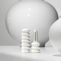 Minimalist white lip balm tube with raised ring design and smooth balm tip on neutral background
