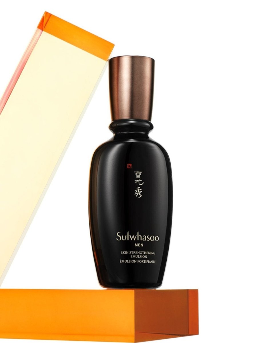 Dark sleek bottle of men's emulsion with bronze cap emphasizing moisture retention on white and orange geometric background