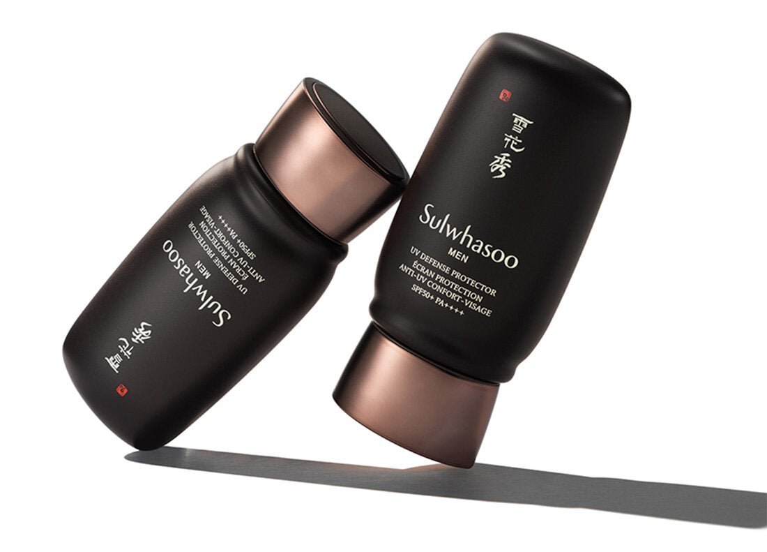 Two matte dark brown tubes of Sulwhasoo men sun protection lotion with bronze caps on white background