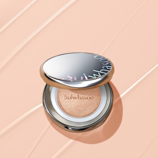 Open silver compact cushion foundation with natural beige tone on soft peach background showing smooth texture swatches