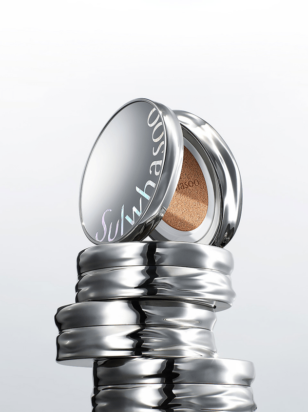 Stack of shiny silver cushion compact cases with one open revealing lightweight foundation sponge inside