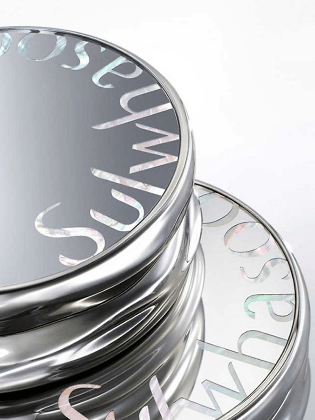 Stacked silver compact cases with reflective surfaces and subtle iridescent text on a white background