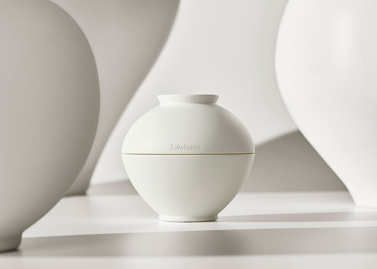 Minimalist white round jar of creamy skincare product emphasizing youthful appearance in soft neutral setting