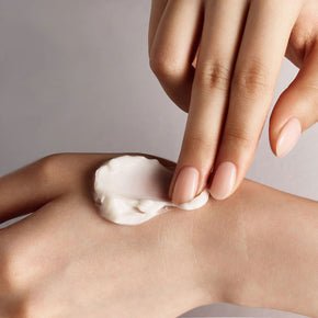 Creamy texture of skin-smoothing lotion being gently applied on hand to promote a youthful, radiant appearance