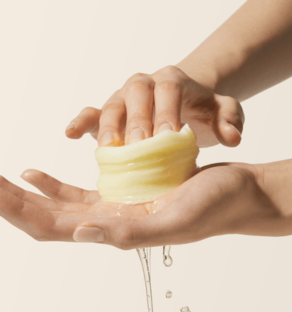 medicube Deep Vita C Pad 150g (70 Pads) showing hands squeezing translucent cotton pad with brightening essence dripping