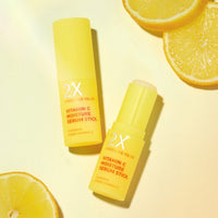 Yellow serum stick container with brightening moisture formula placed next to fresh lemon slices on pale background