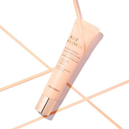 Peach-colored tube of wrinkle-reducing face cream with gold cap on white background with peach lines